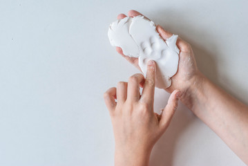 kid hands while working with polymer clay on a light background, soft focuse, relationship education concept