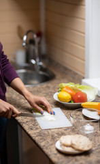 Female hand cuts vegetables for salad.