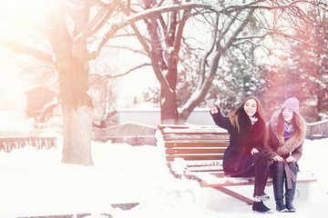 Fototapeta premium A young girl in a winter park on a walk. Christmas holidays in the winter forest. The girl enjoys winter in the park.
