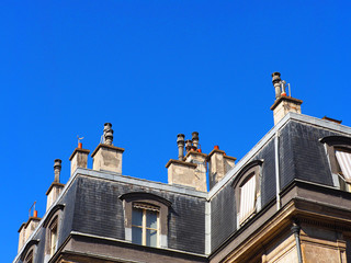 Roofs of a medieval european city. Rooftop, chimneys against the blue sky, Paris, France.  Attic, garret, mansard