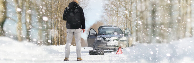 A man near a broken car on a winter day