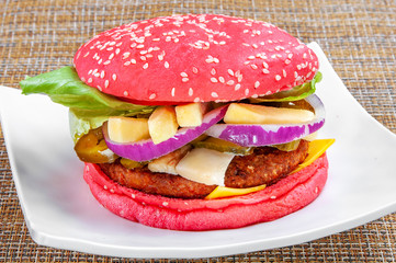 Classic hamburger with red bread and fresh vegetables on a white plate.