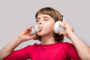 Little girl with headphones chewing gum on white