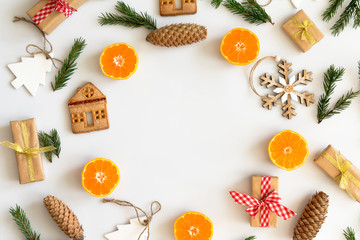 Round frame of Christmas tree branches and decorations with oranges, cookies, gifts, space for text. Top view.