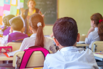 education, elementary school, group of school kids sitting and listening to teacher in classroom