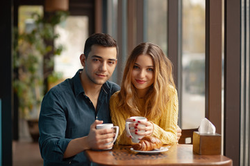 Young couple in love sitting in a cafe, drinking coffee