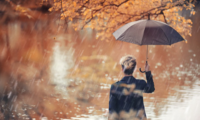 Fototapeta premium Autumn rainy weather and a young man with an umbrella