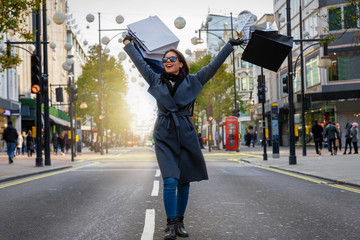 Modische, junge Stadt Frau mit Einkaufstaschen in der Hand auf der Oxford Street in London beim...