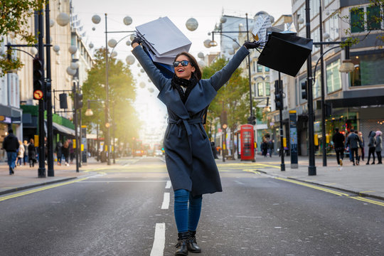 Modische, junge Stadt Frau mit Einkaufstaschen in der Hand auf der Oxford Street in London beim Shoppen 