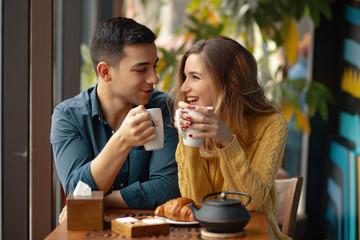 Young couple in love sitting in a cafe, drinking coffee - obrazy, fototapety, plakaty