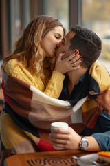 Couple embracing and kissing covered with a blanket