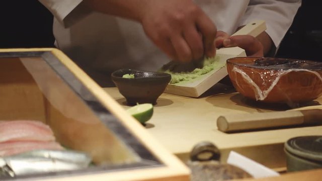 Close-up of a sushi chef preparing wasabi for customers