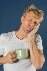 Sleepy man with a mug of hot drink. Early morning