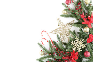 Christmas fir tree branches with baubles and candy canes on white background