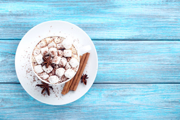 Cappuccino with marshmallows, cinnamon and star anise on blue wooden table