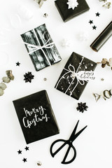 Flat lay, top view of gift boxes with quote "Merry Christmas" , "Happy Holidays" and decorations on white background.