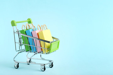Small paper shopping bags with shopping cart on blue background © 5second