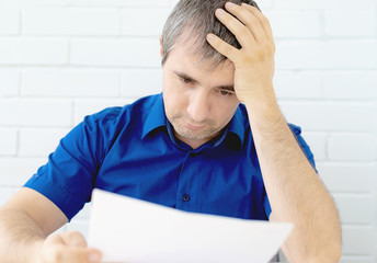 Young worried businessman holding his head. the man is worried holding his head reading a letter...