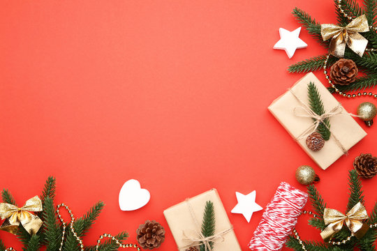 Christmas fir tree branches with gift boxes on red background