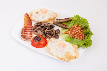 Full english breakfast. Bean, eggs , bacon slices, sausages, tomatoe and mushrooms on white plate