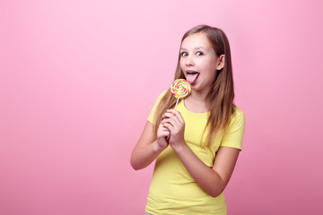 Cute young girl with lollipop on pink background