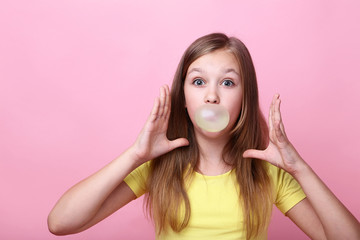 Young girl blowing bubble gum on pink background