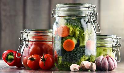 Jars with marinated food and organic raw vegetables