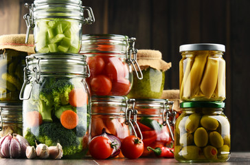 Jars with marinated food and organic raw vegetables