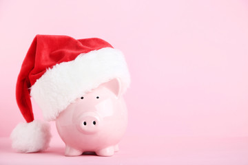 Pink piggybank with santa hat on pink background
