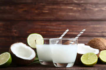 Coconut milk in glasses with limes on brown wooden table