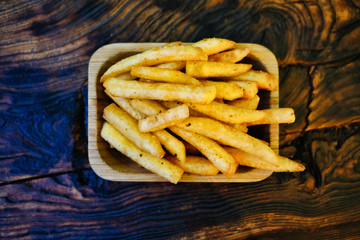 Crispy crispy fries on a rustic wooden table. French fries in a serving platter.