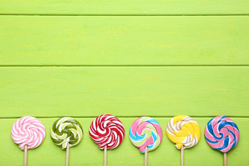 Colorful lollipops on green wooden table