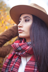 Portrait of a beautiful, young Turkish woman in yellow trees. Warm autumn. Happy brunette walks in the autumn park. The girl in the hat. Fashion.