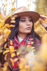 Portrait of a beautiful, young Turkish woman in yellow trees. Warm autumn. Happy brunette walks in...