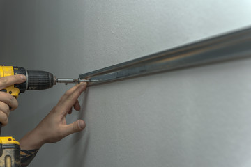 A cabinet maker drills a hole in the wall for later mounting the kitchen cabinets. Concept: craft and service