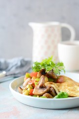 Homemade omelette with mushrooms, vegetables and arugula on a plate. Wonderful healthy breakfast near the window.