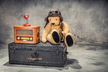 Retro radio, red microphone, Teddy Bear toy with leather aviator's hat and goggles sitting on old...