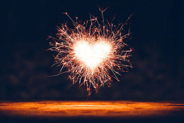 Fototapeta premium Sparklers heart flying above wooden floor. Valentine's day concept