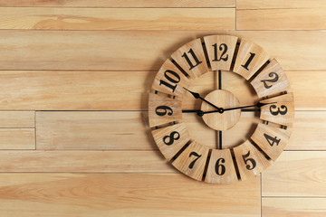 Stylish analog clock hanging on wooden wall. Space for text