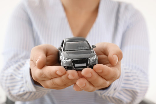 Female insurance agent holding toy car, closeup