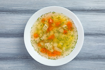 Bowl of fresh homemade soup to cure flu on wooden background, top view