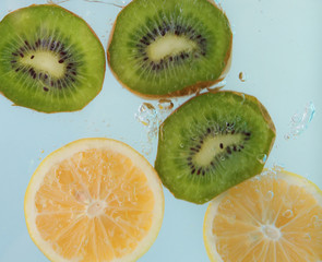  Lemon and kiwi slices splash of water on blue