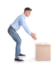 Full length portrait of young man lifting heavy cardboard box on white background. Posture concept