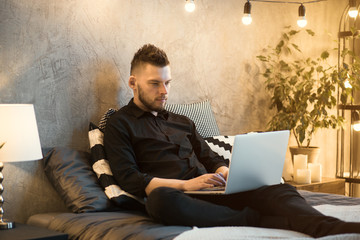 Fototapeta premium Young handsome man working in the home of mobile network company, adapting tariff plans to users need. Consultant providing service online with notebook. Business running through mobile systems. 