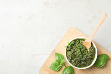 Board with homemade basil pesto sauce in bowl on table, top view. Space for text