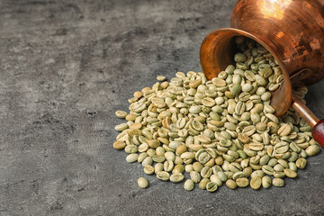Overturned jezve with green coffee beans and space for text on grey background