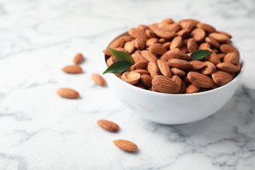 Tasty organic almond nuts in bowl on table. Space for text