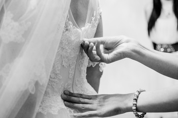 Bridesmaid fastens zipper of bride