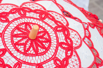 Fototapeta na wymiar A decorative lace umbrella in a Maltese market; white umbrella with red laces.