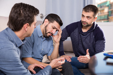 Three anxious men discussing on sofa
